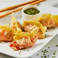 Plato con dumplings de atún, salsa y palitos chinos  