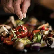  Una persona usando sal para sazonar unas verduras.