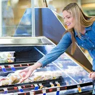 Mujer en supermercado en sección de alimentos congelados 