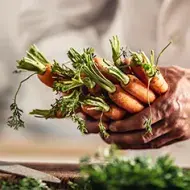 Persona cocinando con zanahorias y creando su plantilla de menú semanal.