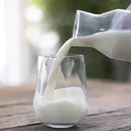 Jarra y vaso con un tipo de leche sobre una mesa de madera