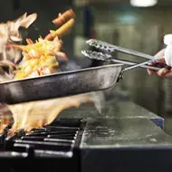 Persona salteando verduras con las precauciones necesarias para evitar quemaduras por aceite