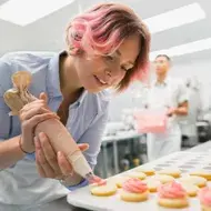 Mujer agrega relleno a galletas con manga pastelera