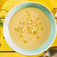 Vichyssoise en un tazón, mesa amarilla con ingredientes frescos