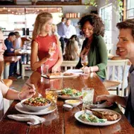 Un anfitrión habla con sus invitados mientras comen