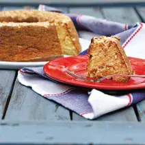 Un plato blanco contiene el pastel y uno rojo una rebanada con un tenedor. Abajo, un paño en azul y blanco.