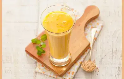 Fotografía en tonos amarillos y blancos tomada desde un banco visto de frente, contiene una tabla de madera y un vaso transparente con una bebida de mango encima. Fotografía en tonos amarillos y blancos tomada desde un banco visto de frente, contiene una tabla de madera y un vaso transparente con una bebida de mango encima.